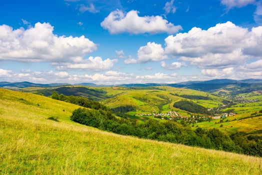 village in the valley of Carpathian mountains. lovely countryside scenery in early autumn with clouds on a blue sky over the distant ridge
