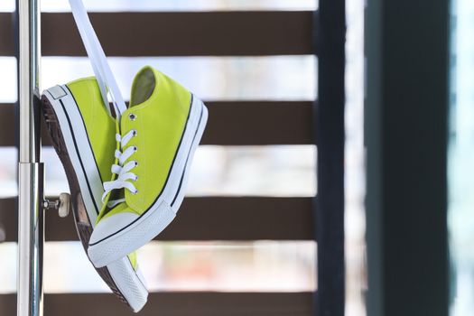 Pair of new green sneakers hanging on clothes line