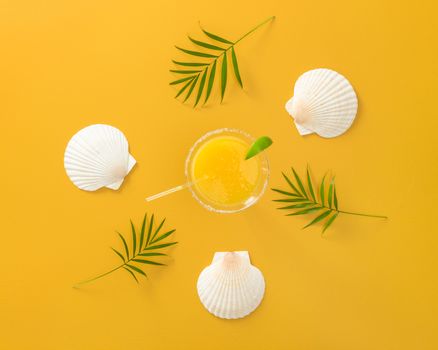 Tropical cocktail on bright summer background with palm leaves and seashells.