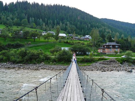Suspended wooden bridge across a rugged little mountain river
