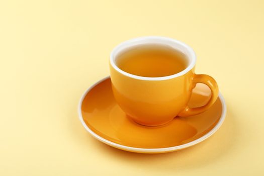 Yellow cup of green oolong tea on saucer