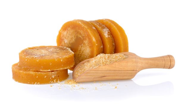 Sugarcane Hard Molasses or Jaggery and sugar in scoop on white b