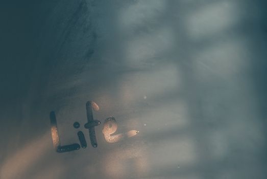 Abstract conceptual background, misted-up window glass with written word on it, life concept