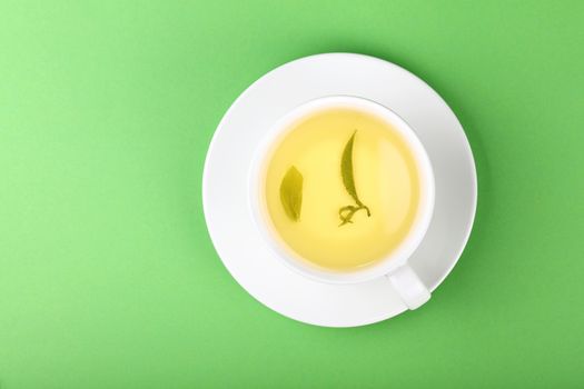 White cup of oolong tea over green