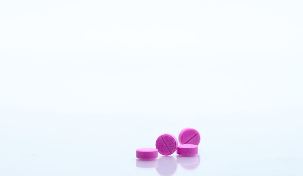 Macro shot of four small pink tablets pills isolated on white background with copy space for text. Medicine for asthma treatment concept. Pharmaceutical industry. Pharmacy background. Global healthcare concept. Health budgets and policy.