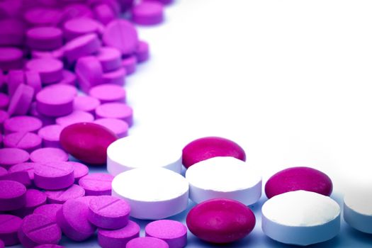 Purple and white tablets pills on white background with copy space. Toxicology. Pharmaceutical industry. Pharmacy background. Narcotic drug. Drug addict.