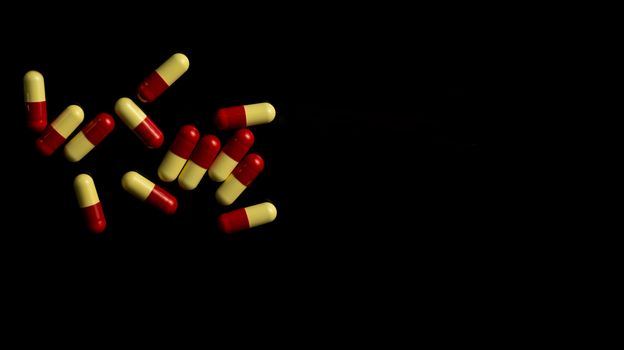 Red, yellow capsule pills on dark background. Antimicrobial resistance concept. Pharmaceutical industry. Pharmacy background.