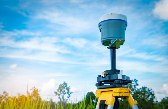 GPS surveying instrument on blue sky and rice field background