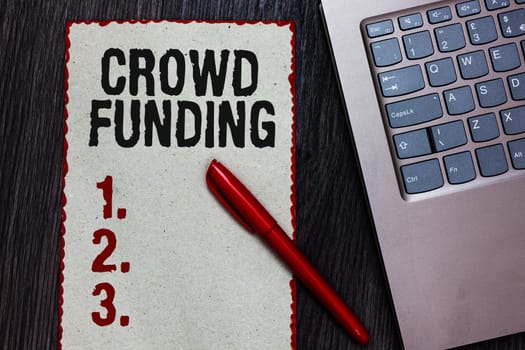 Handwriting text writing Crowd Funding. Concept meaning Fundraising Kickstarter Startup Pledge Platform Donations Piece paper red borders black marker computer keyboard wooden background.