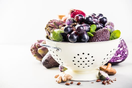 Purple fruits and vegetables in colander - space for text
