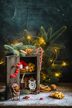 Magic wooden cupboard with gingerbread cookies, cinnamon, alarm clock, mug of tea, nuts and dried cranberries