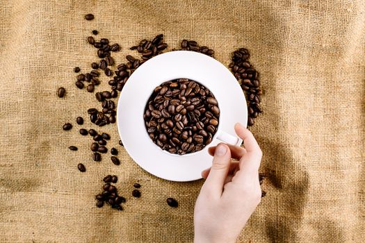 Hand reaching for a mug with coffee beans