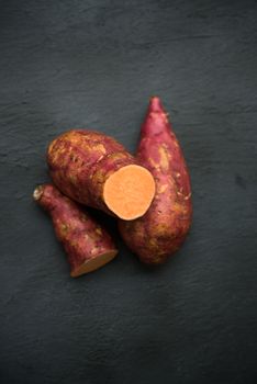 Raw orange sweet potatoes on wooden surface. Top view.