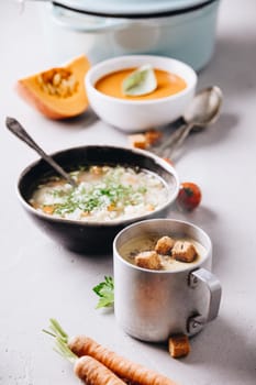 Pea, tomato, vegetable soups and ingredients on concrete background