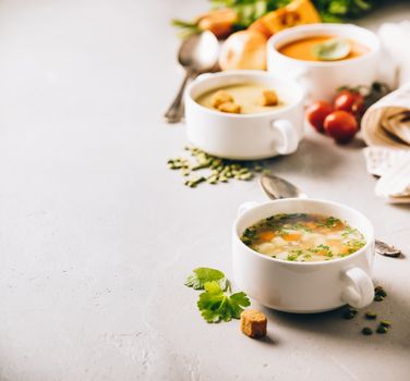 Pea, tomato, vegetable soups and ingredients on concrete background