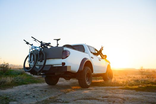 Friends Driving Pickup Offroad Truck in the Mountains with Bikes in the Body at Sunset. Adventure and Travel Concept.