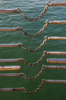 chain connects two metal bars over body of water
