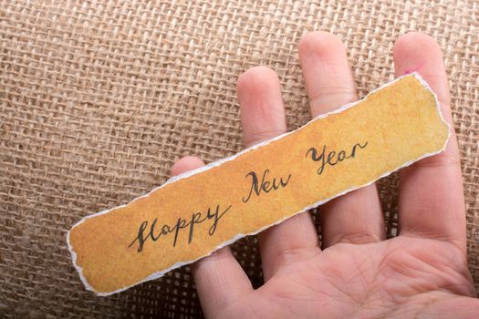 Happy new year written on a torn paper in hand