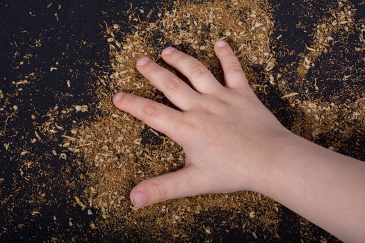 Toddlers hand on tobacco on black ground