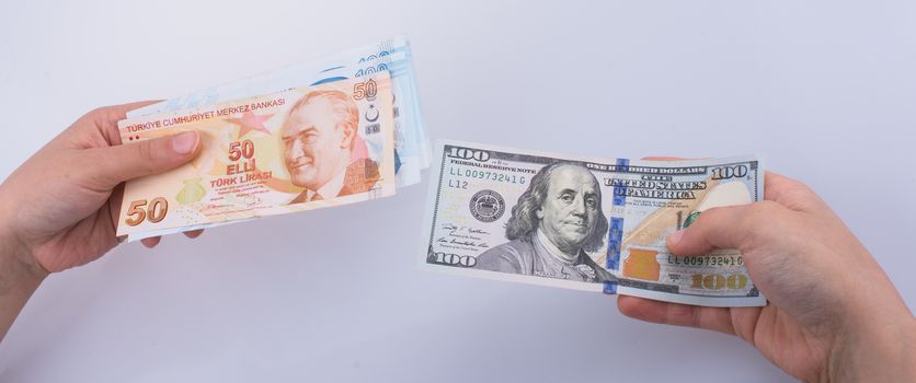 Hands holding American dollar banknotes and Turksh Lira banknote