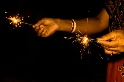 Mother and kid holding sparklers on black background
