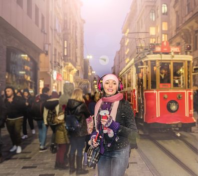 Beautiful woman in beanie poses in front of nostalgic tramway