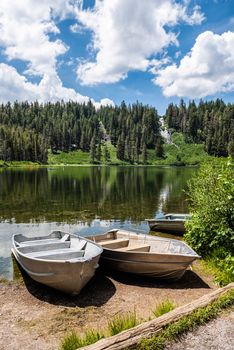 Boats docked on shore in Twin Lakes with  Twin Falls in the background in Mammoth Lakes, California