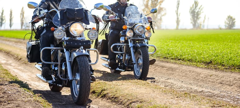 Two Motorcycle Drivers Riding Custom Chopper Bikes on an Autumn Dirt Road in the Green Field. Adventure Concept.