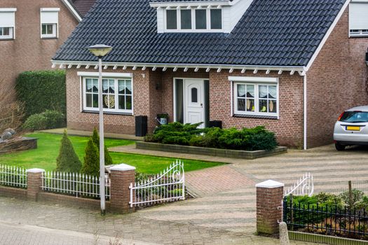 luxurious dutch bungalow from street view, with beautiful garden and a gate, modern dutch architecture, home in a small village of the Netherlands