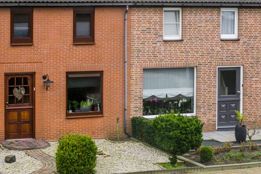 Modern dutch terraced house exterior with gardens, plants behind the windows, homes in a dutch village