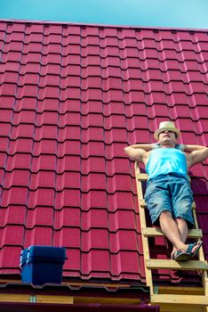 A worker takes a sun bath on the roof of the house during a brea