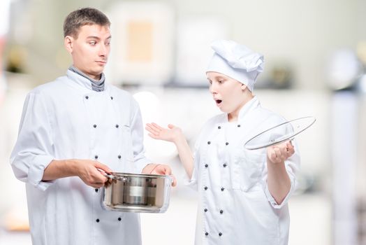 surprised cook looks at soup in a pan of another chef on the bac