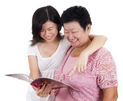 Senior mother and young daughter reading on a book, with smiling, isolated on white background.
