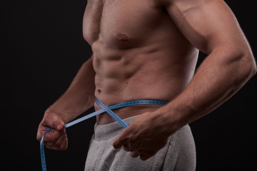 bodybuilder with a measuring tape around his stomach