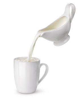 Pouring cream from creamer into cup with splash isolated on white background, flowing milk