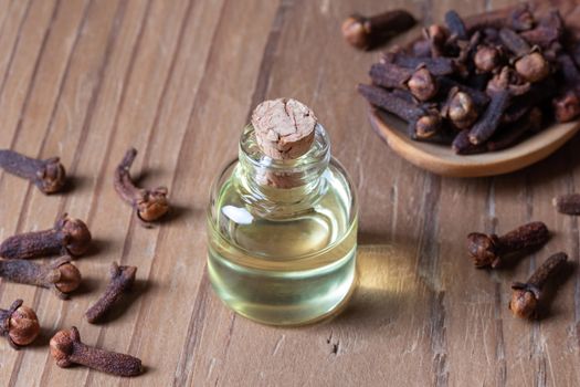 A bottle of clove essential oil with cloves