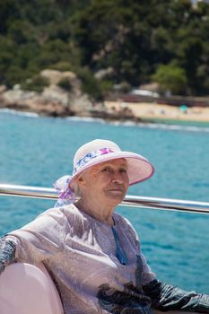 Senior woman enjoys summer vacation in a sea voyage on a pleasure boat.