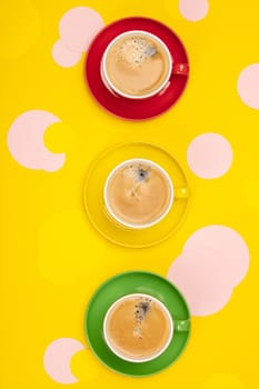 Cups of Coffee and colorful paper circles on yellow paper backgr