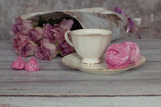Romantic still life with a cup of coffee and marshmallows in a cozy ambience with roses