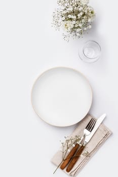 Empty white plate and cutlery on a napkin 