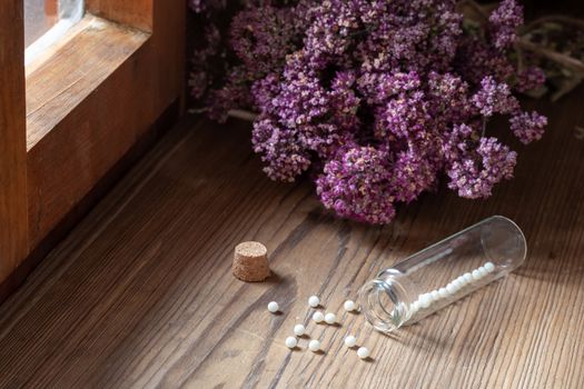 A bottle of homeopathic pills with dried herbs