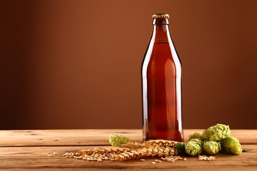 Close up brown beer bottle, hops, barley on table