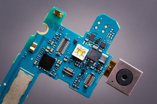 Blue circuit board from smartphone with camera module on a ribbon cable.
