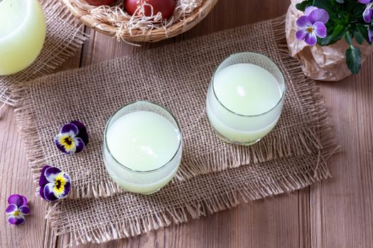 Two glasses of fresh whey and pansy flowers