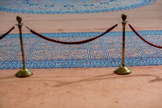 Velvet rope and metal stand near blue carpet in display