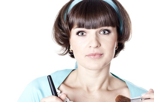 Attractive brunet woman in blue dress with two make-up brushes