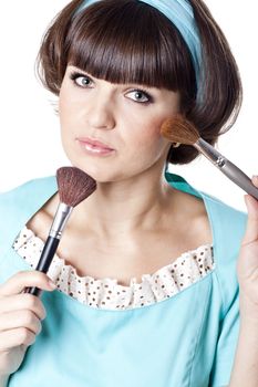 Attractive brunet woman in blue dress with two make-up brushes