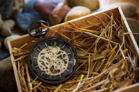 Pocket watch winder on natural wheat straw in a wooden box. Conc