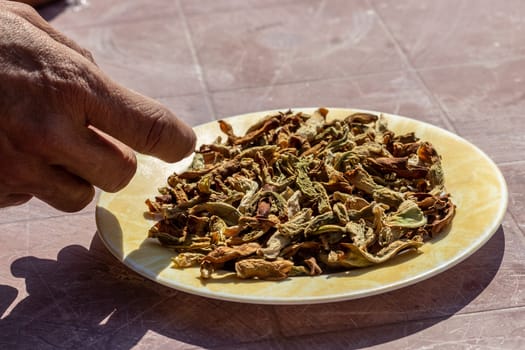 a side view shoot to dried peppers on plate with a person touchi