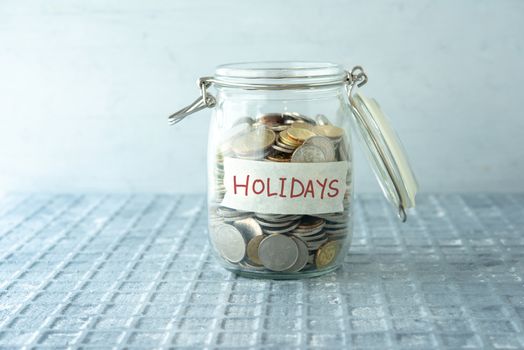 Coins in glass money jar with holidays label, financial concept.